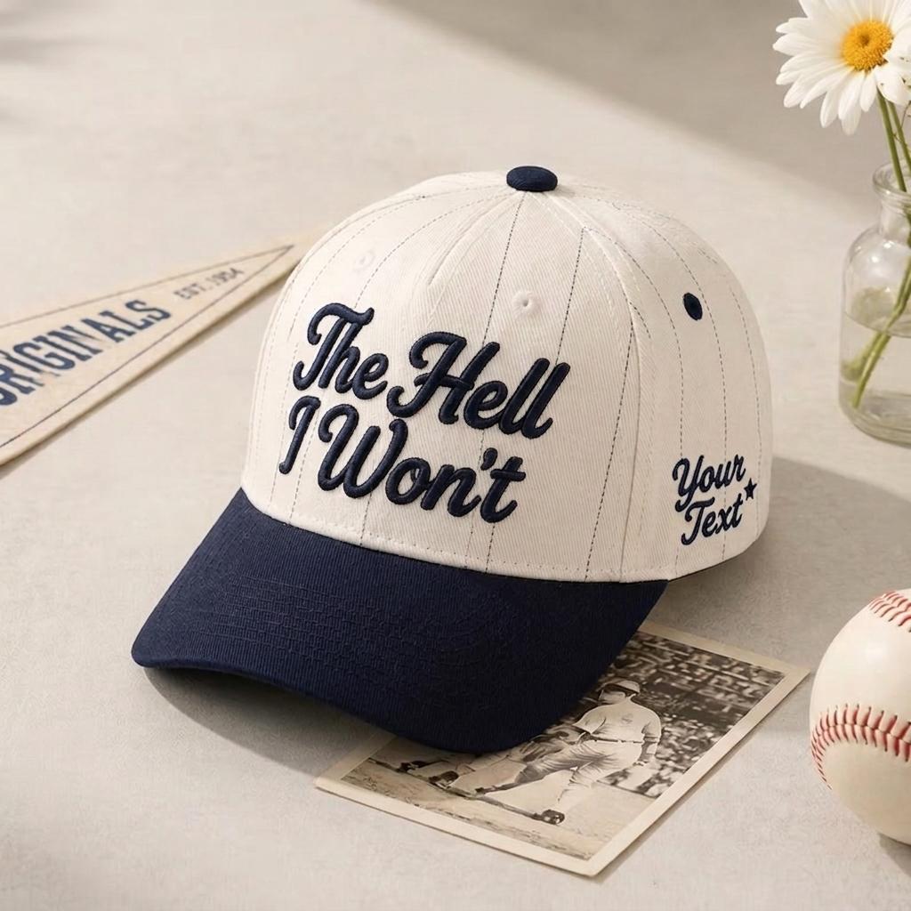 White pinstripe baseball cap with navy bill and “The Hell Won’t” front lettering