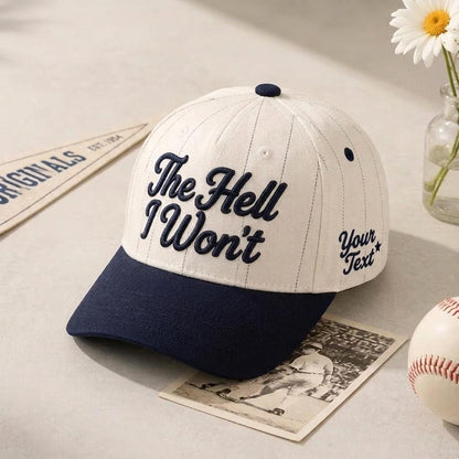 White pinstripe baseball cap with navy bill and “The Hell Won’t” front lettering