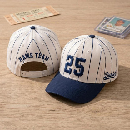 Cream and navy pinstripe baseball hat displayed on a wood surface with embroidered 25 and Daniel side script