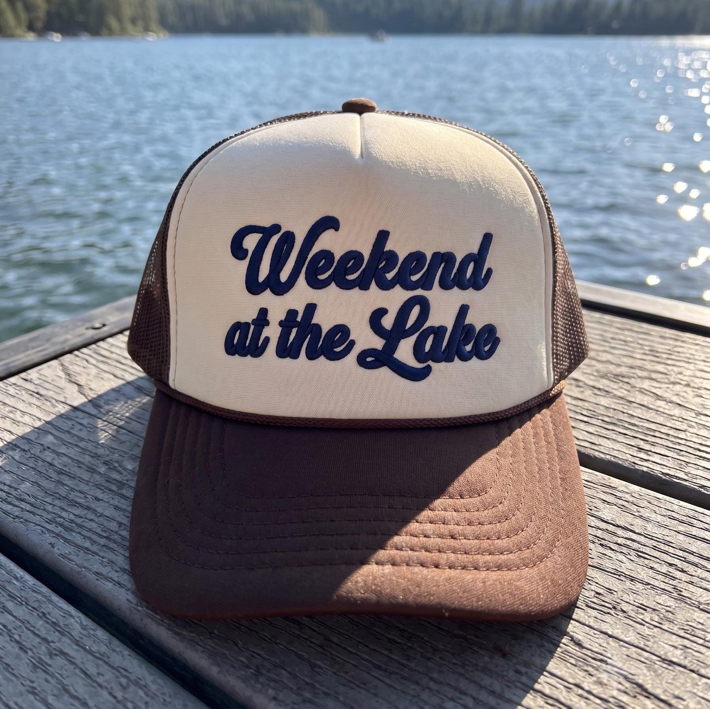 Weekend at the Lake embroidered trucker hat displayed on a wooden dock