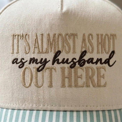 Close-up of embroidered It’s Almost as Hot as My Husband Out Here quote on a cream hat