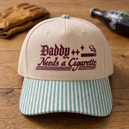 Retro embroidered statement hat with light blue striped bill on a wooden table