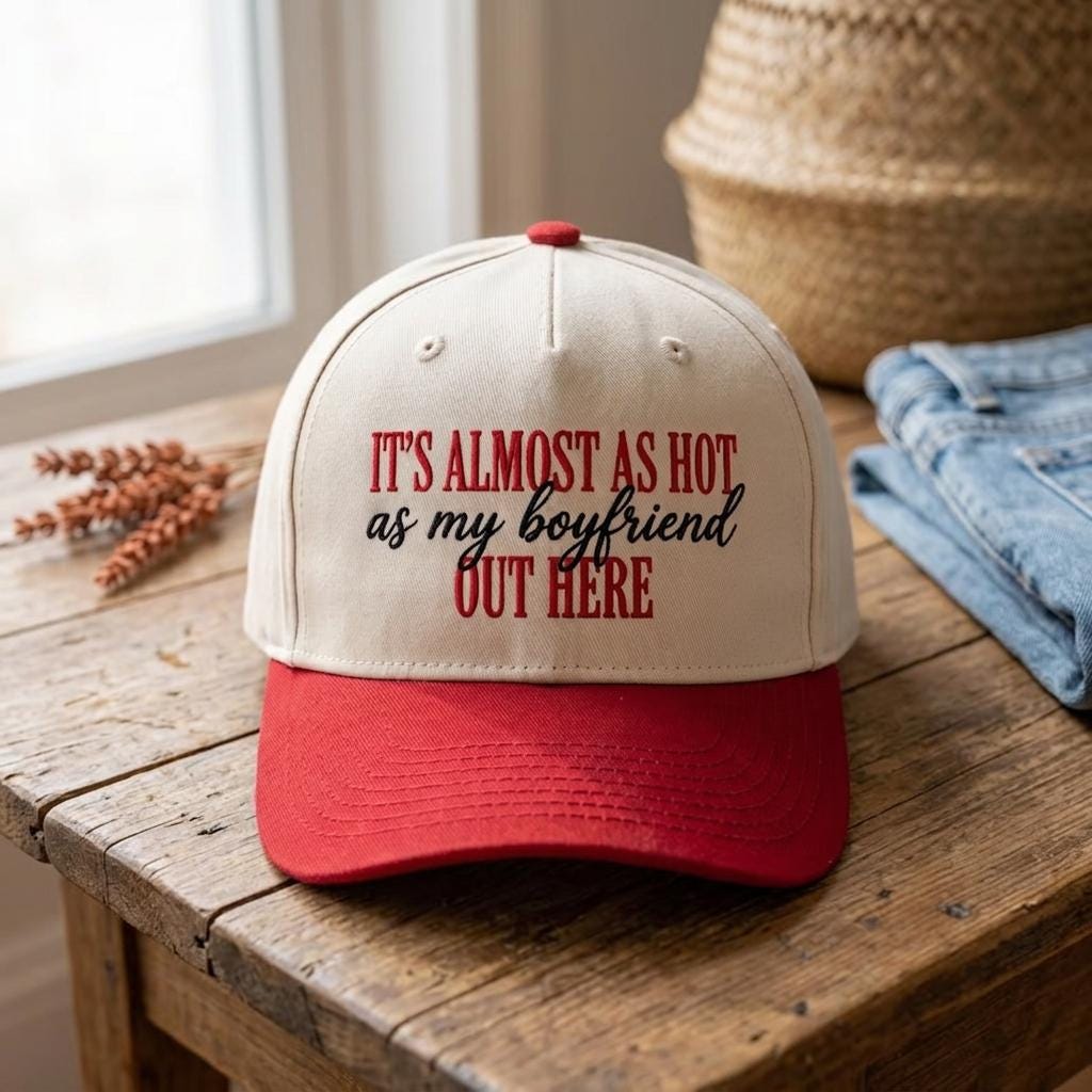 Front view of a cream and red funny quote trucker cap on a wooden table