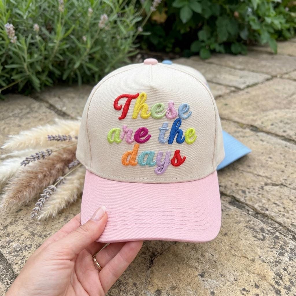 Pink-brim embroidered hat featuring the phrase “These are the days” outdoors