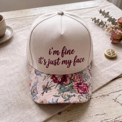 Embroidered floral brim hat displayed on a rustic tabletop
