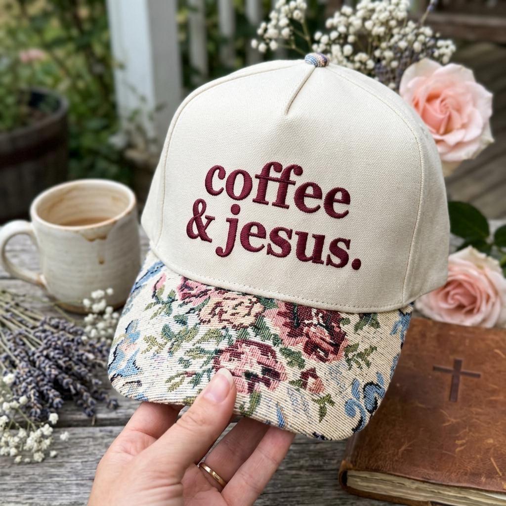 Cream Christian hat embroidered with “coffee & jesus.” and finished with a floral-patterned brim