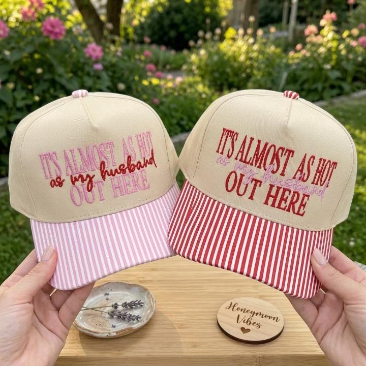 Khaki embroidered hat with “It’s almost as hot as my husband out here” quote and pink striped bill