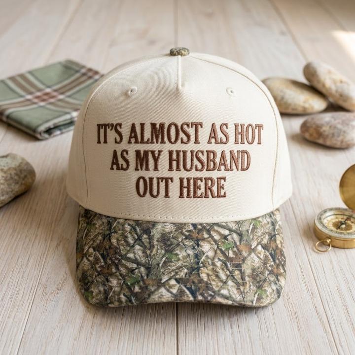 Funny cream cap with brown embroidered text and camo brim on a rustic tabletop