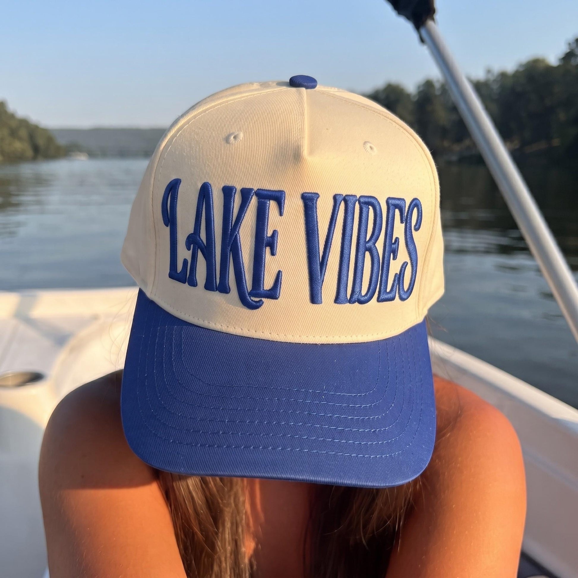 Cream and blue embroidered Lake Vibes hat photographed on a boat