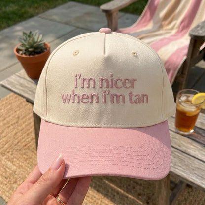 Cream and pink two-tone trucker hat embroidered with “I’m nicer when I’m tan”