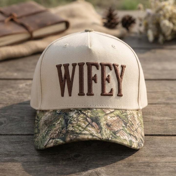Front view of cream Wifey hat with brown embroidery and camouflage bill