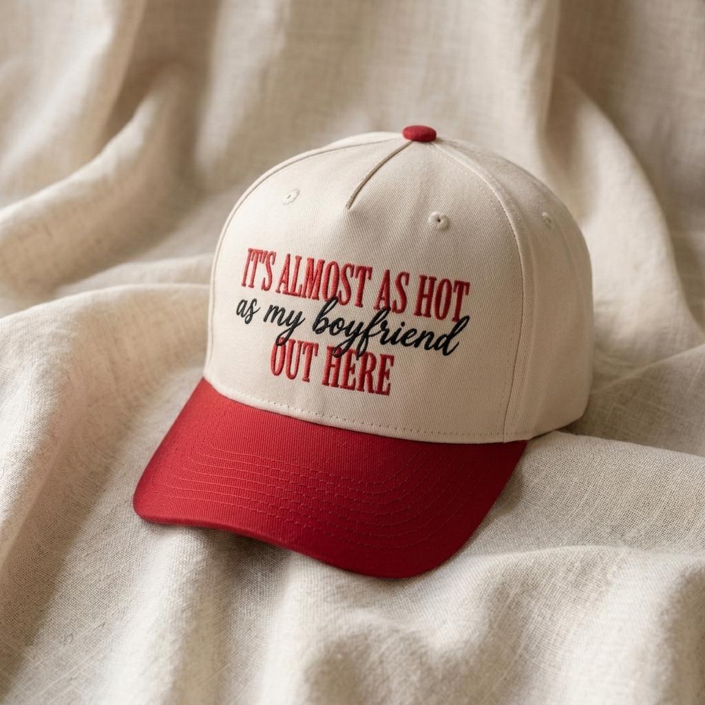 Cream and red two-tone trucker cap with “It’s Almost as Hot as My Boyfriend” lettering on the front