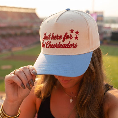 Person wearing a light cheerleader hat with embroidered message and light blue brim