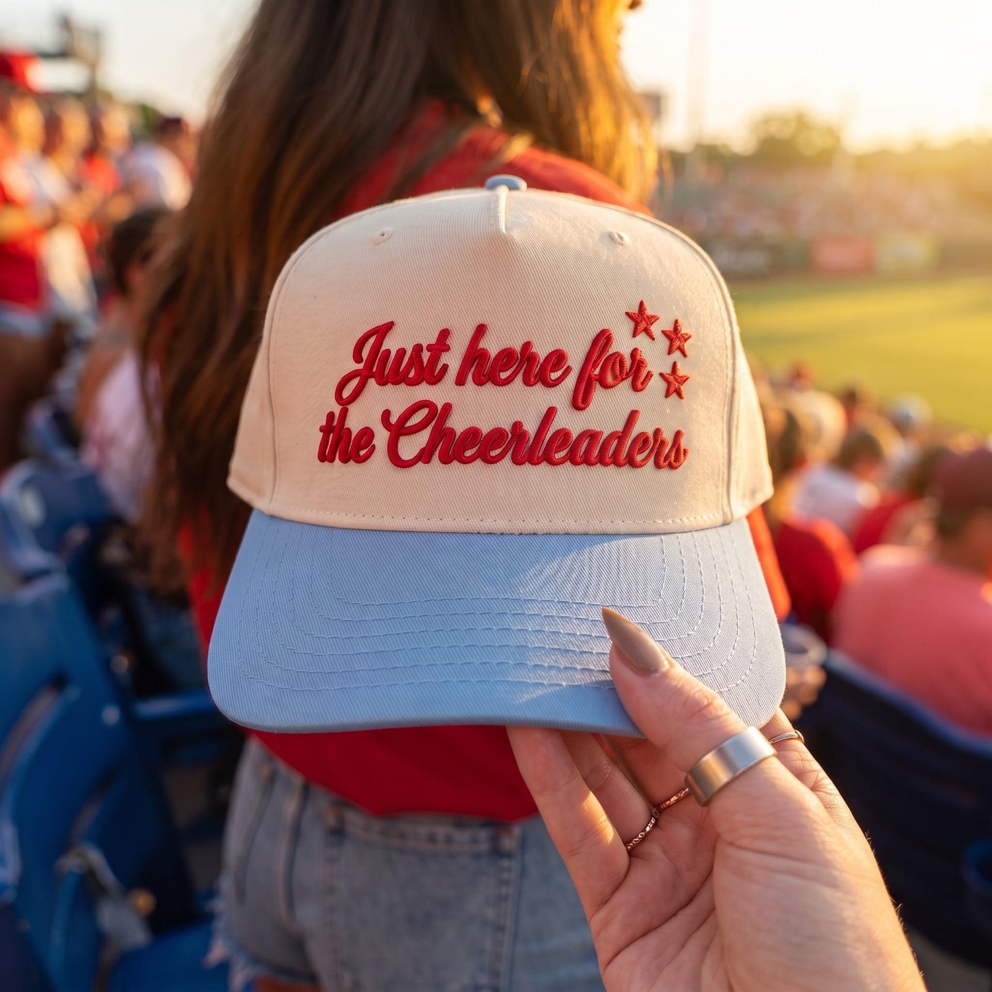 Close-up of red embroidered cheerleader message and stars on a hat in stadium seating