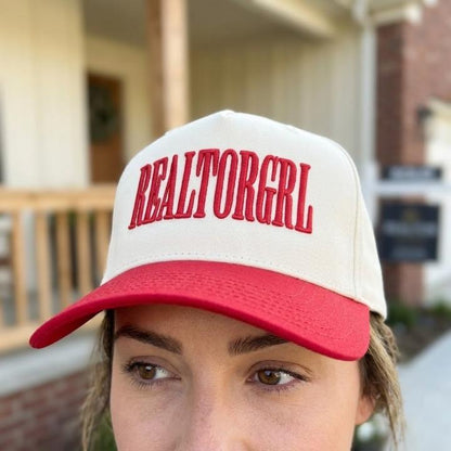 Person wearing a two-tone REALTORGRL cap with a red bill