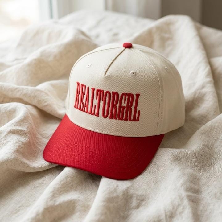 REALTORGRL embroidered cap resting on a bed