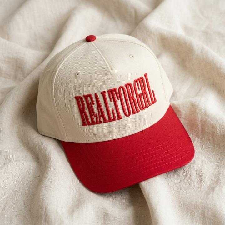 Angled view of cream and red REALTORGRL two-tone cap