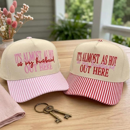 Matching khaki embroidered hats with pink and red striped bills displayed outdoors