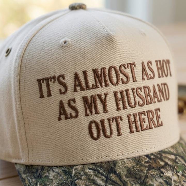 Close-up of brown embroidered lettering on a cream hat with camo brim