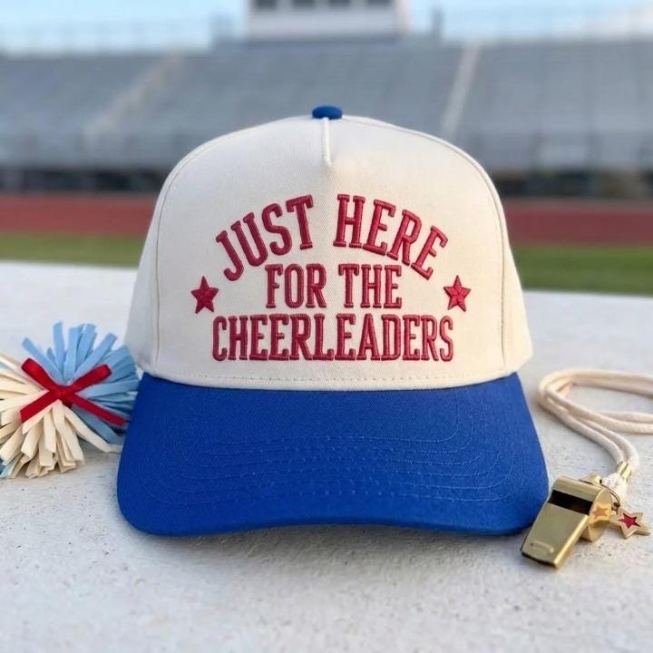 Cheerleader supporter hat with off-white crown and blue brim displayed at a stadium