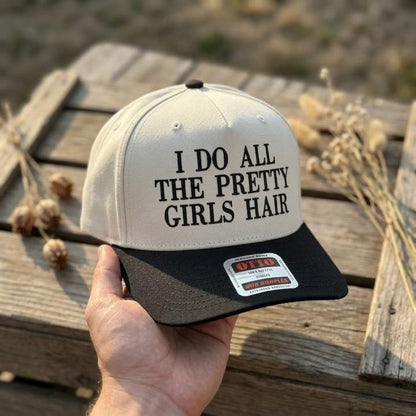 Cream and black two-tone trucker hat reading I Do All the Pretty Girls' Hair