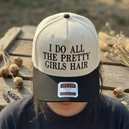Person wearing a cream and black hair stylist statement trucker hat