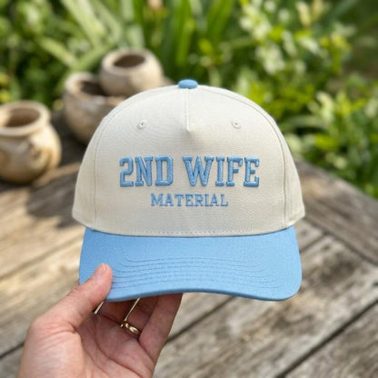 Two-tone 2ND WIFE MATERIAL embroidered hat held outdoors