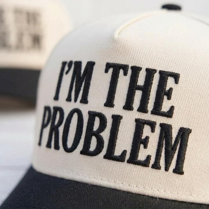 Close-up of embroidered I’m the Problem lettering on a cream hat