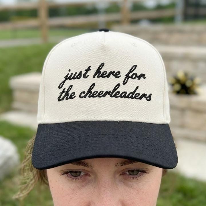 Person wearing the two-tone hat with cheerleader message embroidery