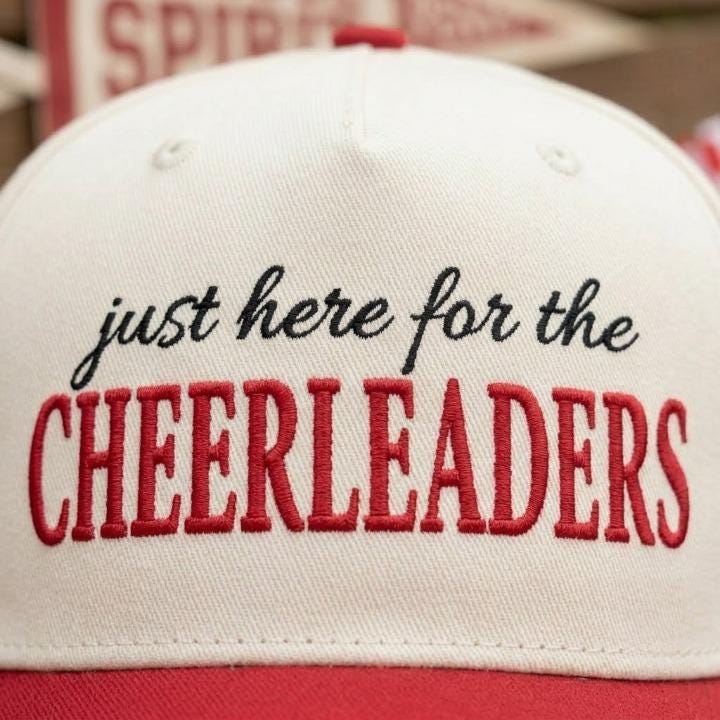 Close-up of black and red embroidered cheerleaders message on cap