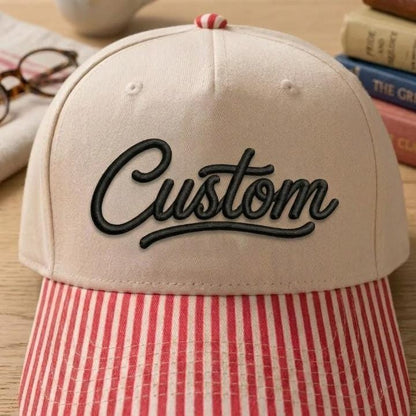 Close-up of khaki Custom script hat with red striped brim