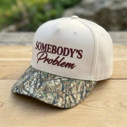 Angled view of Somebody’s Problem hat showing the cream crown and camo bill