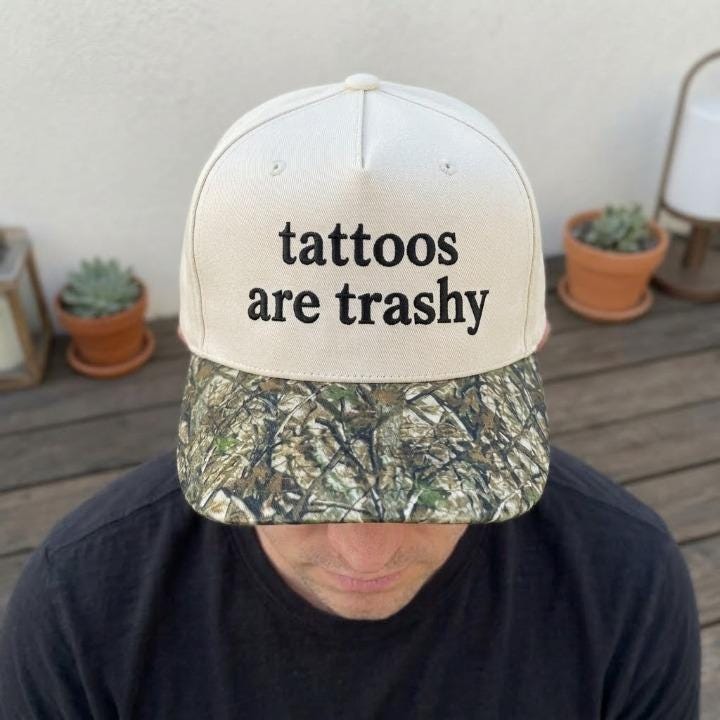 Person wearing a cream statement hat with camouflage-patterned brim