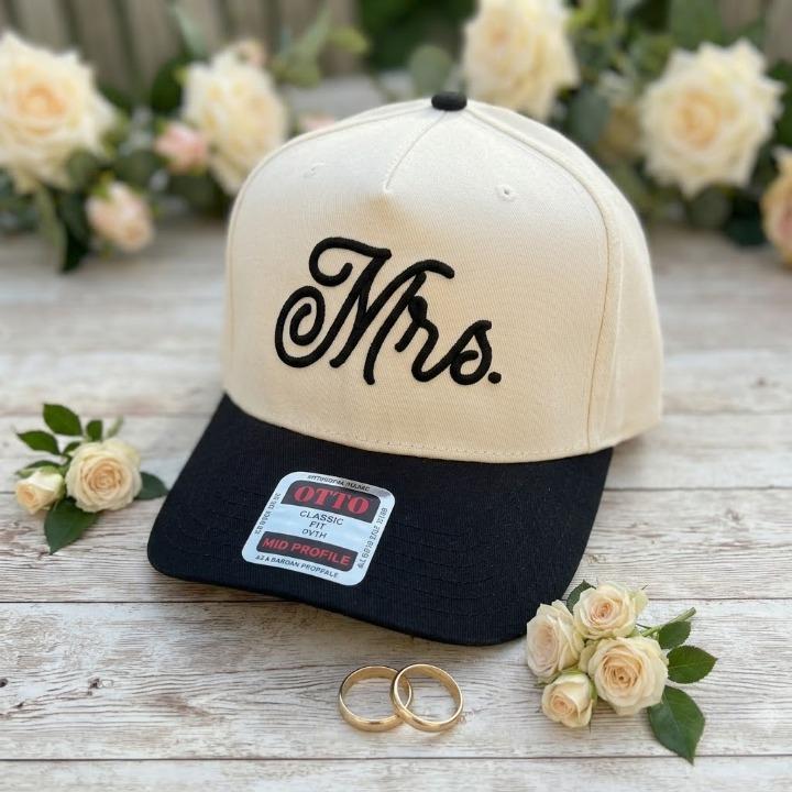 Cream and black Mrs. embroidered hat shown with wedding flowers